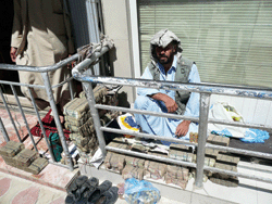 A trader sits inside Shahzada market, surrounded by bricks of local currency, the afghani
