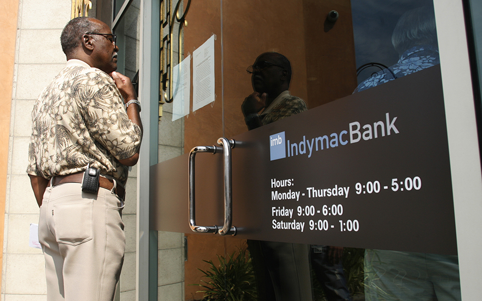 A customer reads a notice posted on the door of a closed branch of IndyMac Bank in Burbank