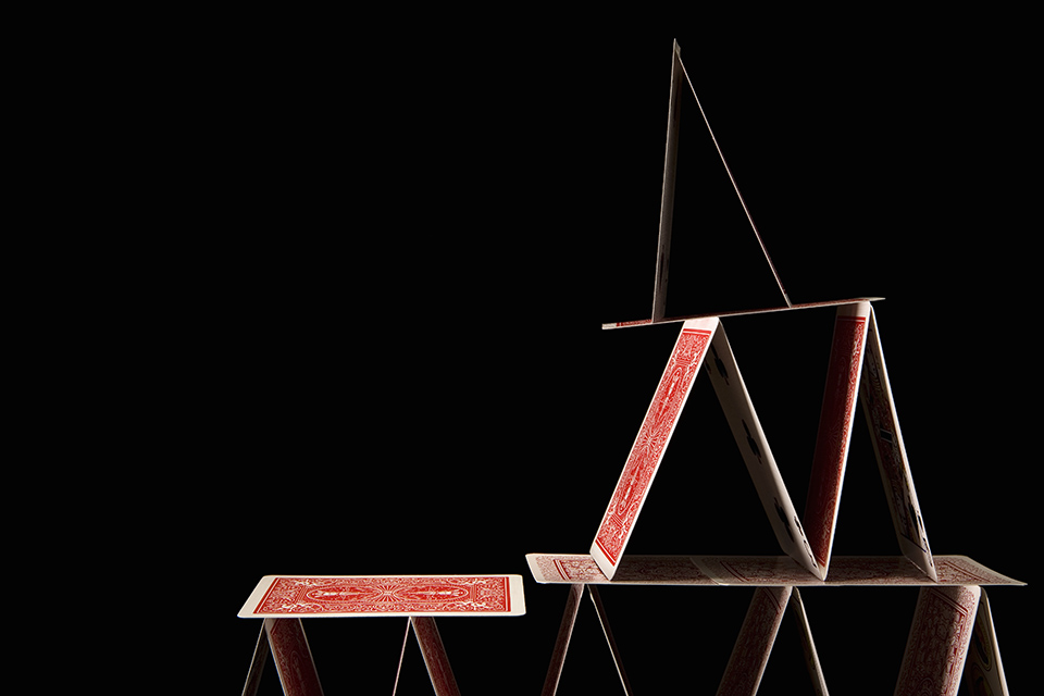 Top of house of playing cards about to topple